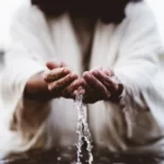 Jesus in the river holding water dripping