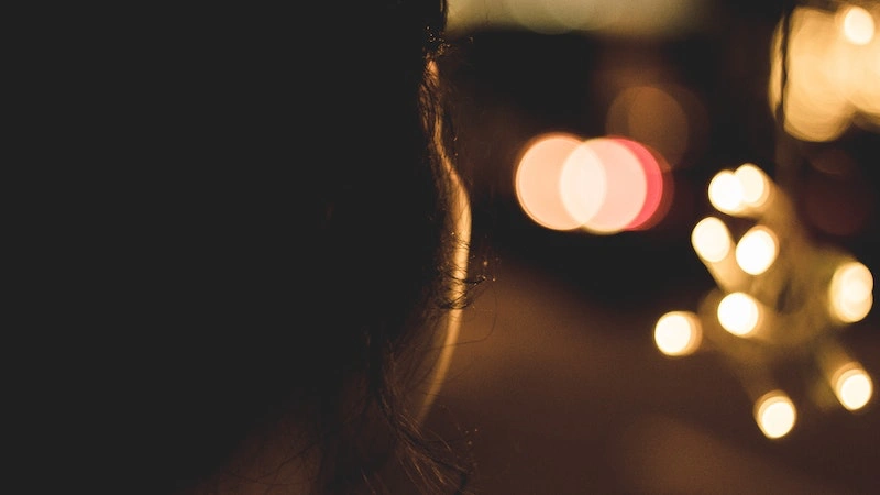close up of the back of the head of a woman with blurred lights in the background