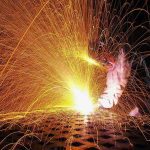 man working with metal and sparks flying