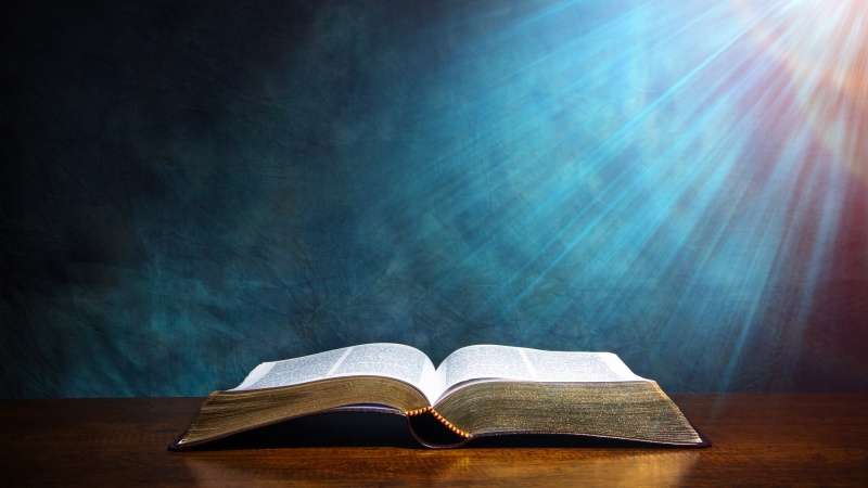 Open bible with light on it blue background