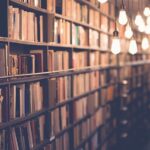 أرفف بها كتب لا حصر لها في غرفة معتمة تتدلى من السقف أضواء صغيرة