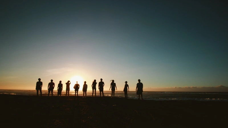 group of people standing at sunset