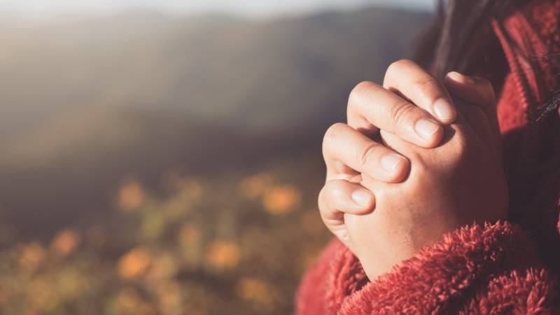 woman folding her hands in prayer