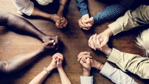 Group of interlocked fingers praying together