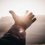 رجل يرتدي قفازًا عند الوصول إلى الشمس في الشتاء