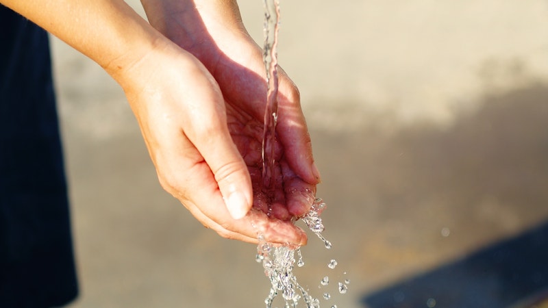 امرأة تغسل يديها تحت الماء الجاري النظيف