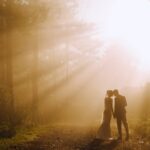 زوجان متزوجان حديثًا في الغابة والشمس في الخلفية