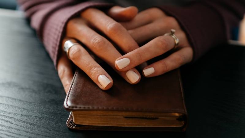 Praying hands of woman on bible