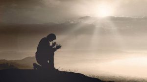 Prayer kneeling and praying to God on mountain autumn sunset background