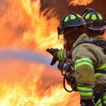 two firemen putting out a fire with water