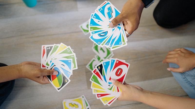 three people showing their hands playing uno