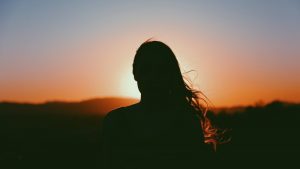 woman with long hair staring into sunset